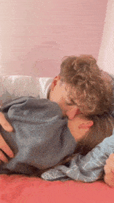 a man is kissing a woman on the forehead while laying on a bed
