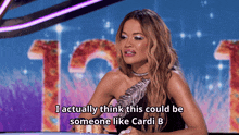 a woman sitting at a table with the words i actually think this could be someone like cardi b above her