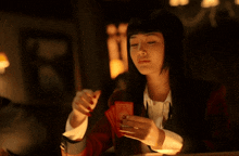a woman in a red jacket is playing cards