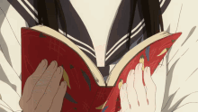 a girl is reading a book with a red cover