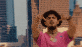 a man in a pink shirt with the number 1900 on his neck is making a peace sign