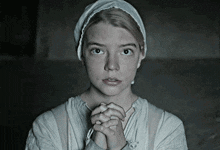 a woman with her hands folded in prayer is wearing a white head scarf