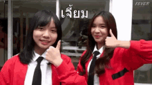 two girls are standing next to each other and giving a thumbs up sign .