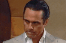 a man in a suit and white shirt is making a silly face .