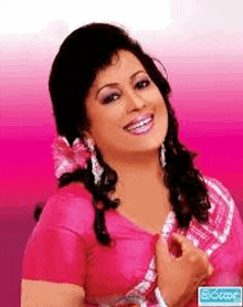 a woman in a pink dress is smiling and wearing earrings .