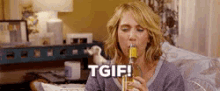 a woman is sitting on a couch drinking from a bottle and saying `` tgif '' .