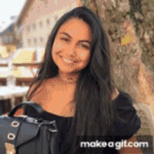 a woman with long hair is smiling and holding a black purse .