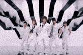 a group of young men in white standing in front of a black and white background