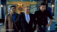 three men are standing in front of a sign that says cid on it