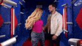 a man and a woman are standing next to each other on a red carpet in a room with security cameras .