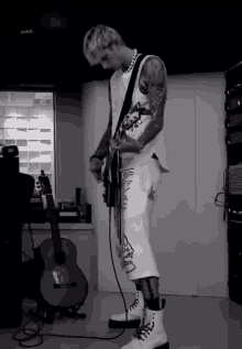 a black and white photo of a man playing a guitar with a guitar in the background