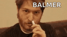a man with a beard is holding a cigarette in his mouth .
