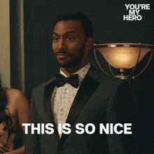 a man in a tuxedo says " this is so nice " in front of a lamp