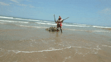 a person in a robot costume holding two swords on a beach