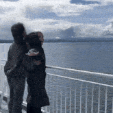 a couple standing on a railing overlooking the ocean