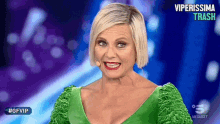a woman in a green dress is smiling in front of a screen that says #gfvip on it