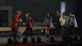 a group of people are standing on a stage in front of arrows