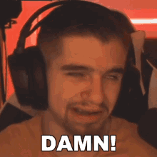 a man wearing headphones is making a funny face and saying damn .