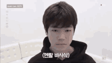 a young man wearing a black hoodie is sitting on a couch .