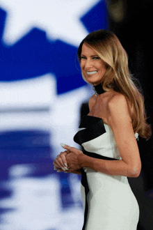 a woman in a black and white dress smiles with a blue star in the background