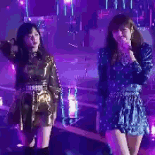 two women are dancing on a stage in front of purple lights .