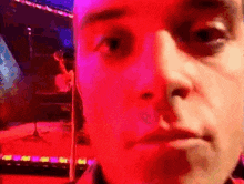 a close up of a man 's face with a microphone in the background and a red light behind him .