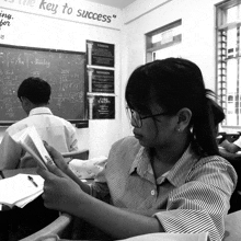 a girl sits at a desk in front of a blackboard that says " the key to success " on it