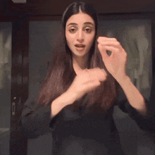 a woman in a black jacket holds her hands up