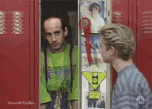 two men are standing in front of a red locker .