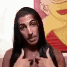 a man with long hair is giving a thumbs up sign .