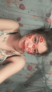 a woman is laying on a bed with red kisses on her face