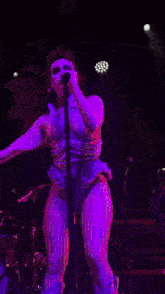 a woman in a purple dress is singing into a microphone on stage .