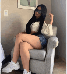 a woman wearing shorts and sunglasses sits on a chair
