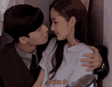 a man is kissing a woman on the forehead while a woman is hugging him .