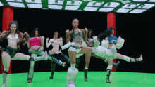 a group of women are dancing on a green screen with one wearing a shirt that says ' abercrombie & fitch '