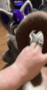 a person is holding a stuffed animal with a purple tail .