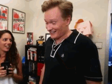 a man and woman are standing in a room with a pitbull poster on the wall behind them