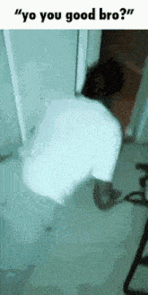 a man in a white shirt is standing in a doorway and talking to someone .