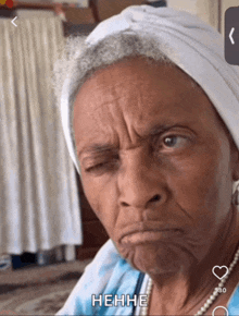 an elderly woman with a white head scarf on her head is making a funny face and the caption says hehhhe