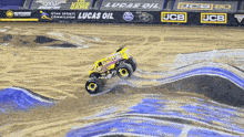 a monster truck is driving on a track with a lucas oil banner behind it