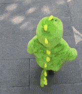 a green dinosaur costume is being worn by a child .