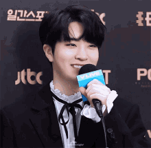 a man in a suit holds a microphone that says vlive on it