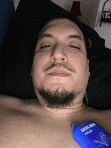 a man with a beard is laying in bed with a geek bar pulse on his chest