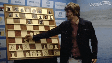 a man playing a game of chess with tata steel advertisements behind him