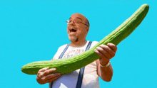 a bald man is holding a very long cucumber in his hands