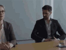a man and a woman are sitting at a table in a conference room