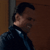 a man wearing a blue shirt and a black jacket has an arrow on his jacket