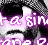 a man with a beard wearing sunglasses and a hat with a purple background that says ta sin