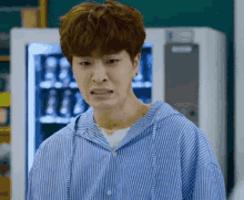 a young man wearing a blue and white striped shirt is making a funny face .