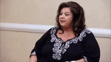 a woman is sitting in a chair wearing a black and white shirt and talking to someone .